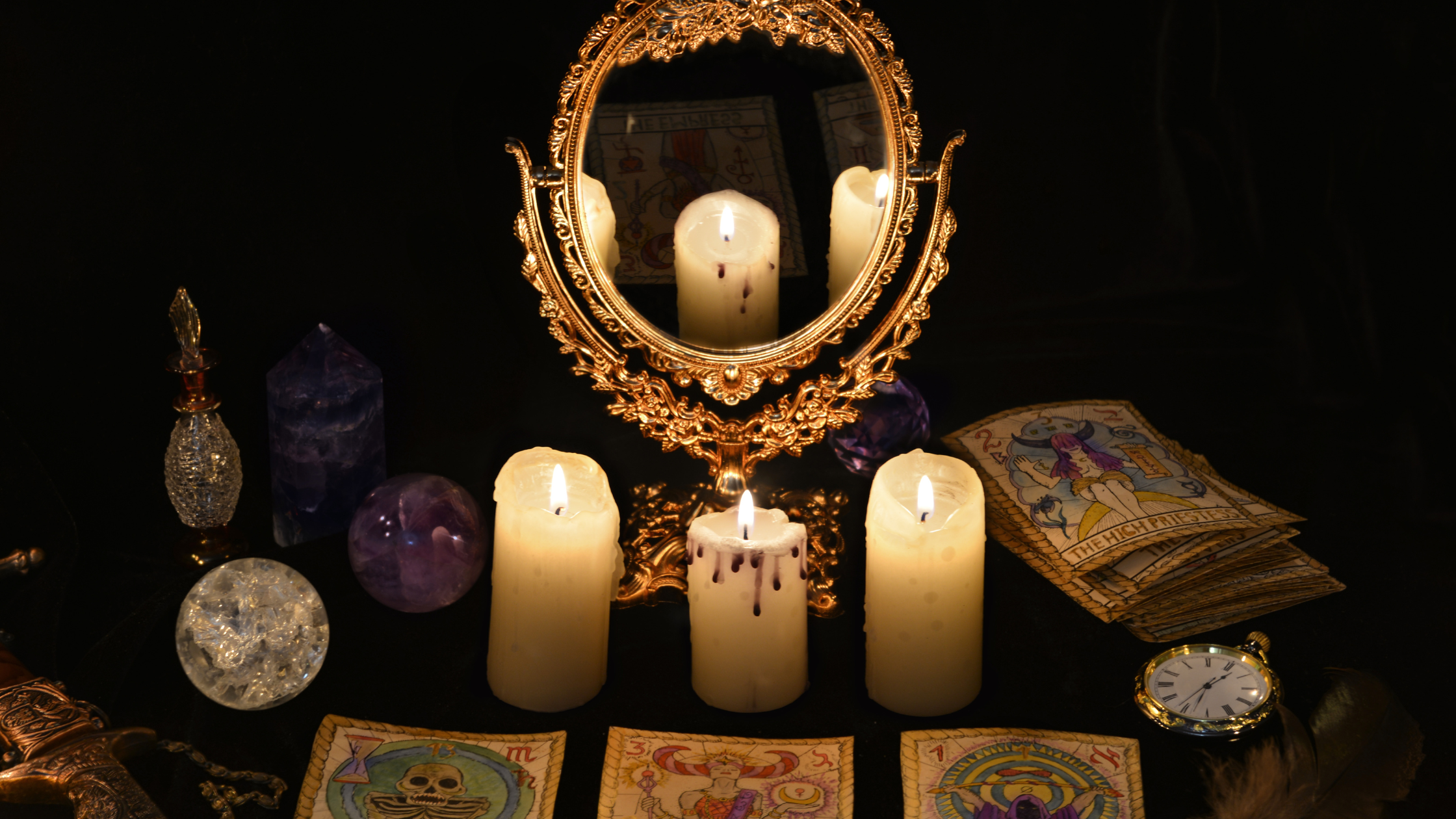 Three lit candles in-between a mirror and tarot cards